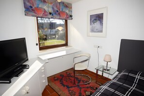 A bedroom with a TV, a window, a chair, a bedside table, and a bed. - Apartment 'Peperoni' with Private Garden and Wi-Fi (Moos)