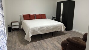 Een slaapkamer met een bed, nachtkastje, kledingkast en stoel.