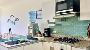 A compact kitchen with a microwave, stove, sink, and a coffee maker. - Beachfront Condo | Caracol Beach, Punta Chame | Pools & Ocean Views (Chame)