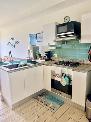 A compact kitchen with a microwave, stove, sink, and a coffee maker.