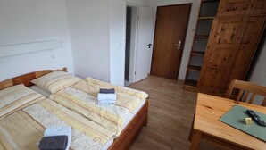 A bedroom with a bed, a wooden table, and a wardrobe.