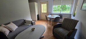 Un salon comprenant un canapé, un fauteuil, une table basse et une table à manger.