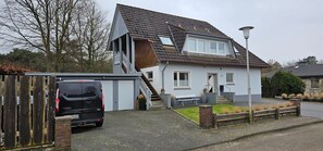 A two-story house with a garage, a staircase, and a small front yard. - Apartment '3 Im Eg' with Wi-Fi (Cuxhaven)