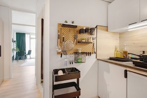 A modern kitchen with a pegboard holding utensils, a sink, and a stove.