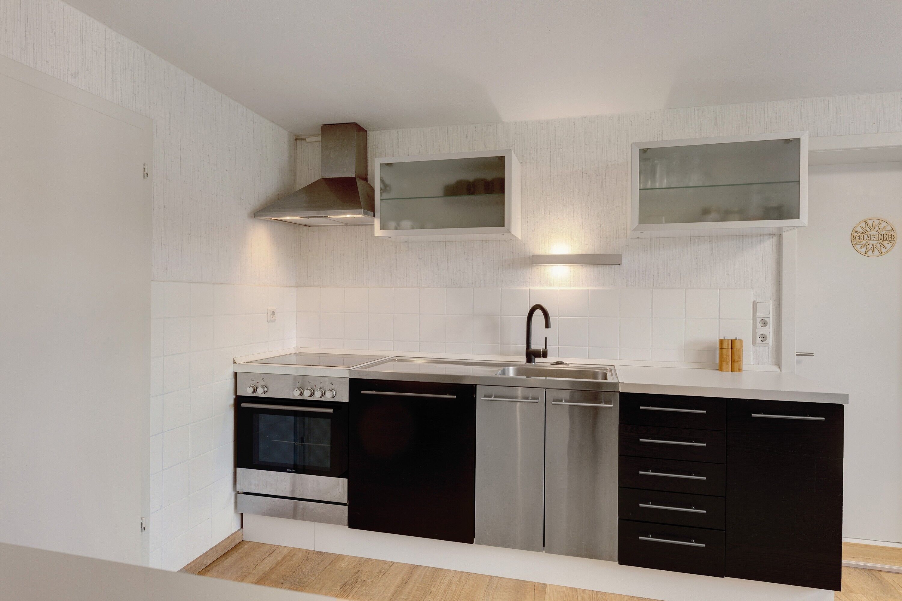 A modern kitchen with a built-in oven, dishwasher, and stainless steel cabinets.