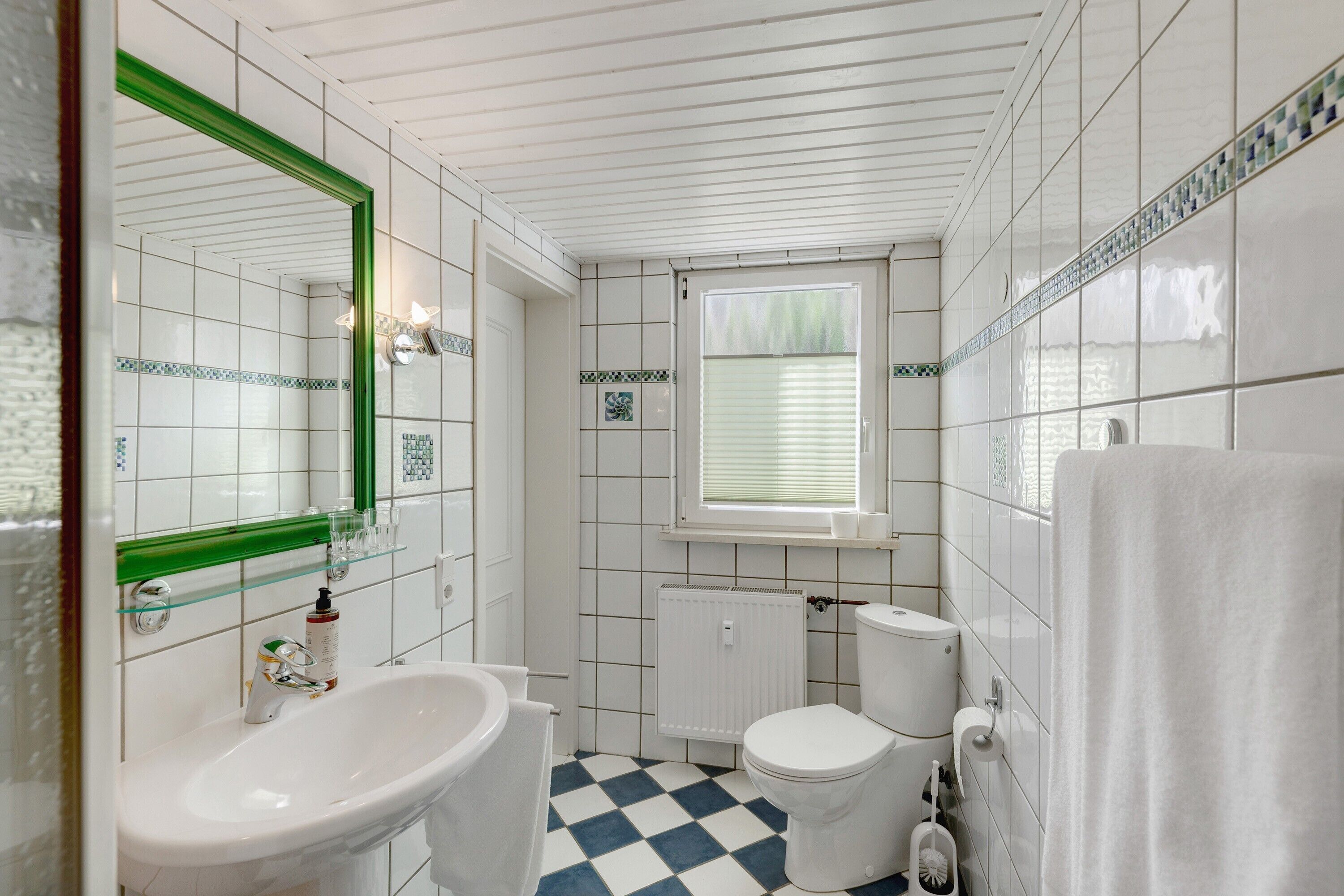 A bathroom with a white sink, toilet, and a window with blinds.