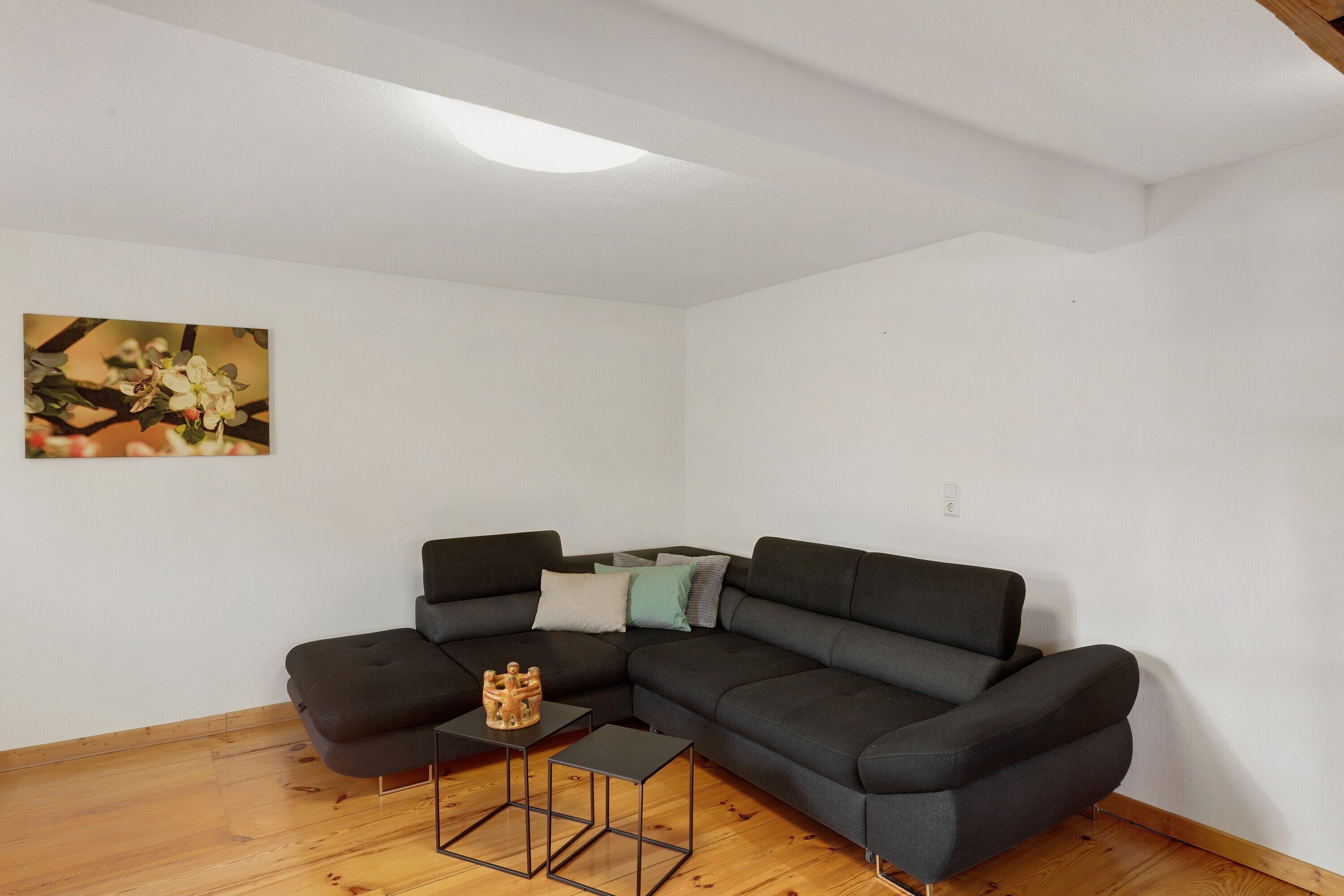 A modern living room with a sectional sofa, a small coffee table, and a painting on the wall.