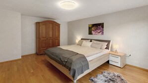 Une chambre à coucher avec un lit en bois, une table de chevet avec une lampe, une armoire et un tableau accroché au mur.