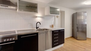 Une cuisine moderne dotée d’appareils électroménagers en acier inoxydable, de meubles de couleur noire et blanche et d’un plancher en bois.