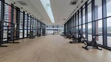 Un gimnasio con equipo de ejercicio, ventanas amplias y piso de madera.