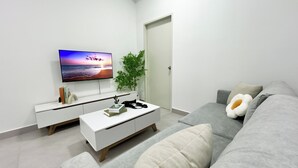 A modern living room with a flat-screen TV, a white console table, a grey sofa, and a potted plant. - 168 Park Selayang by Manhattan Group (Batu Caves)
