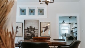A dining area with a wooden table, leather chairs, and framed artwork on the walls. - Luxe Farmhouse near Deep Ellum & Bishop Arts (Dallas)
