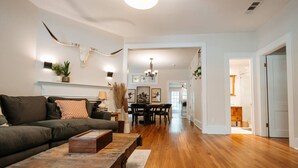 A living room with a sofa, coffee table, and dining area with chairs. - Luxe Farmhouse near Deep Ellum & Bishop Arts (Dallas)