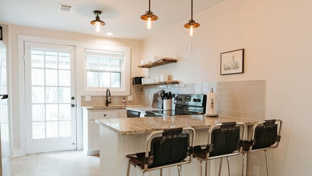 A kitchen with a central island, bar stools, a stove, and pendant lighting. - Luxe Farmhouse near Deep Ellum & Bishop Arts (Dallas)