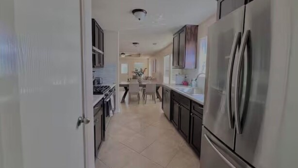 A modern kitchen with stainless steel appliances, a dining area with a table and chairs, and a hallway leading to other rooms.