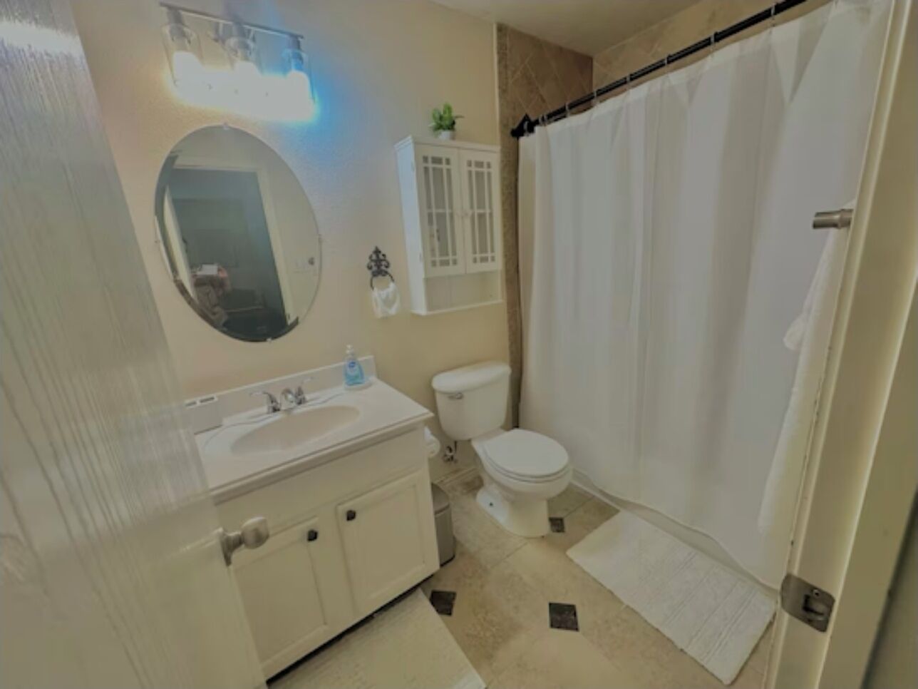 Un baño con lavamanos, inodoro y cortina de ducha blancos.