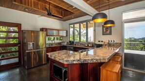 A modern kitchen with a granite countertop, stainless steel appliances, and a large island. - Outstanding ocean view, 4 bdr, jungle villa! (Uvita)