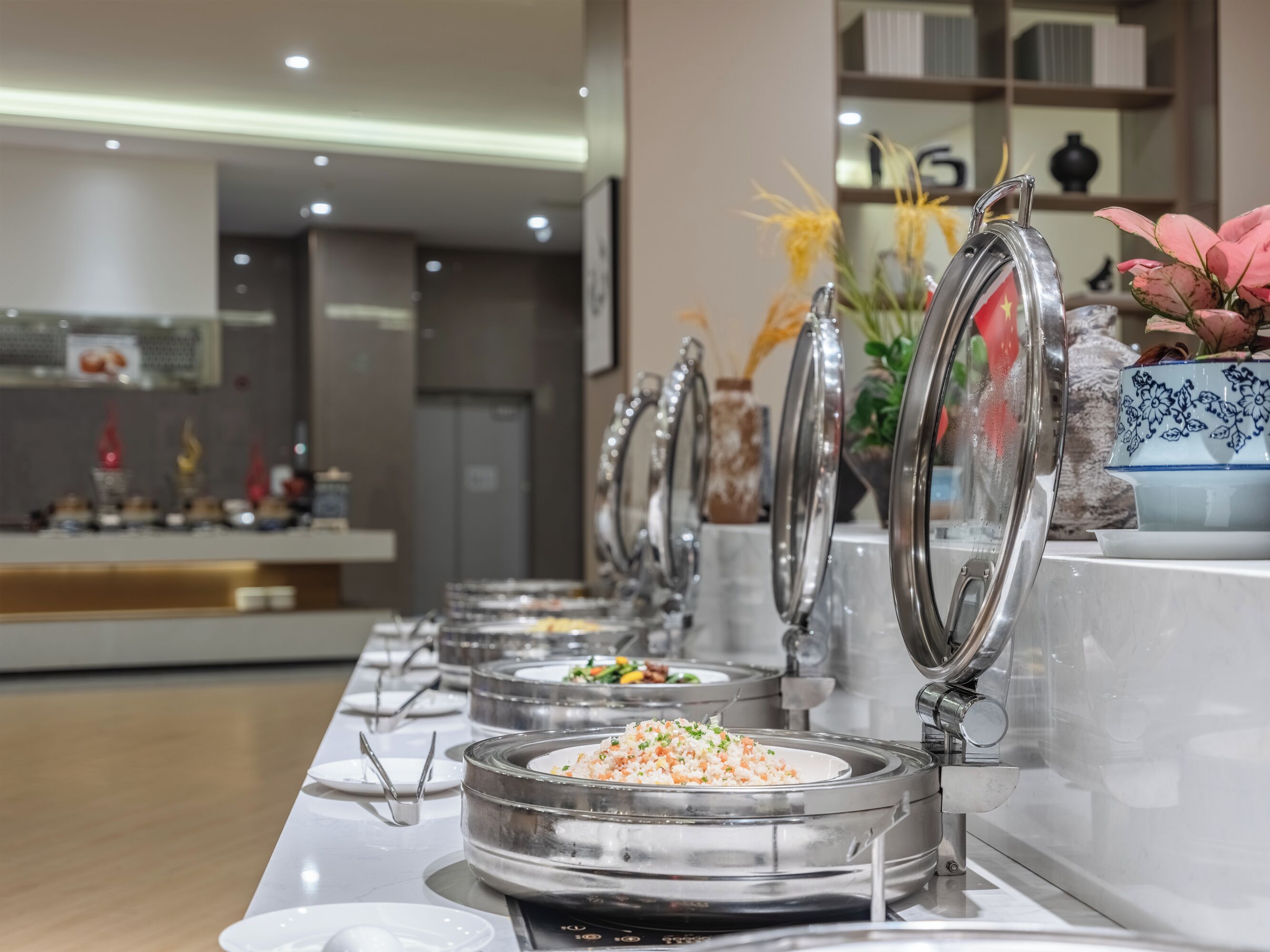 Un buffet composé de plusieurs présentoirs de nourriture, chacun étant équipé d’un plat de service couvert et de couverts.