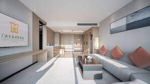 Un moderno vestíbulo de hotel con una recepción, un sofá con cojines, una mesa de centro y una obra de arte grande enmarcada en la pared.