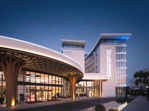 Een modern hotel met een gebogen entreekap en meerdere verdiepingen.