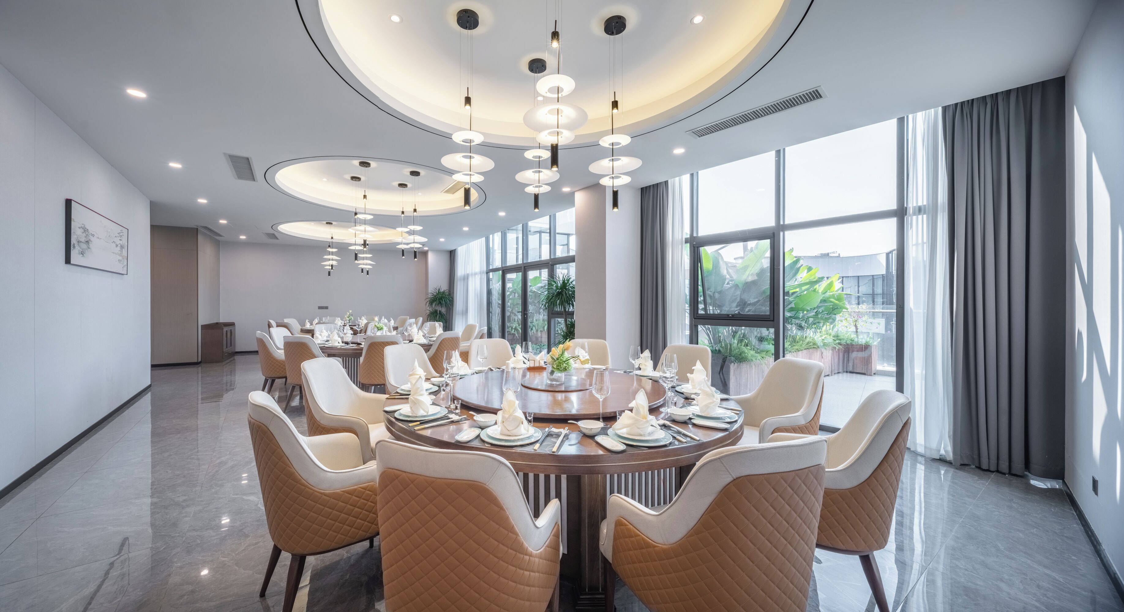 A modern dining area with round tables, beige upholstered chairs, and a ceiling with circular light fixtures.