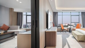 Habitación de hotel moderna con sofá, escritorio y vistas de la ciudad.