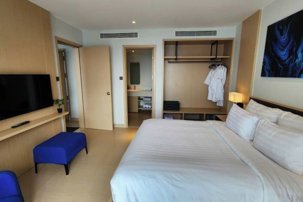 Una habitación de hotel con una cama grande, televisión, armario y un cuadro en la pared.
