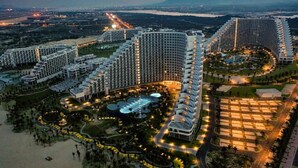 Un gran complejo hotelero con múltiples edificios de gran altura, un patio central con piscinas y una zona ajardinada circundante.