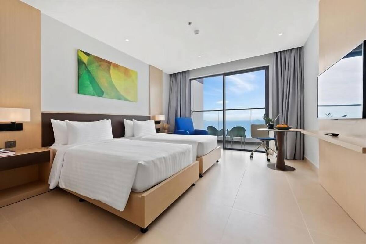 A modern hotel room with two beds, a desk, a chair, and a large window offering a view.