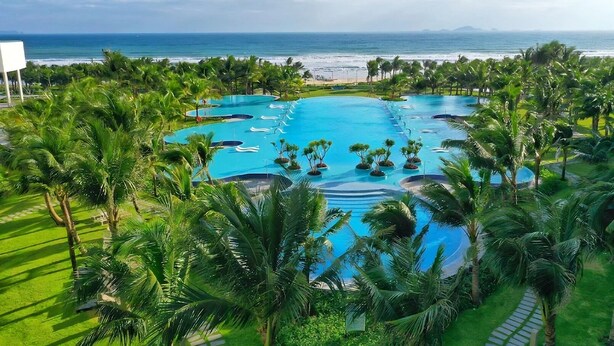 Un resort con múltiples piscinas rodeadas de palmeras y vista al océano.