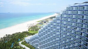 Un hotel moderno con vista al mar, que cuenta con un edificio grande con varios balcones y una zona de piscina.