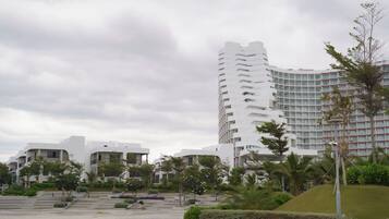 A modern hotel with a curved facade, multiple balconies, and a landscaped courtyard with greenery.