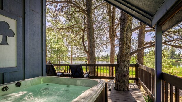 A hot tub on a wooden deck with a view of trees and a body of water. - Lake Front Home, Newly Remodeled, Hot Tub, Game Room, Views! (Pagosa Springs)