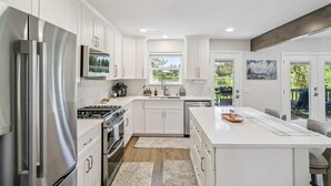 A modern kitchen with white cabinetry, stainless steel appliances, and a large island. - Lake Front Home, Newly Remodeled, Hot Tub, Game Room, Views! (Pagosa Springs)