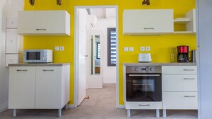 Una cocina compacta con armarios blancos, un microondas, un tostador y un horno.