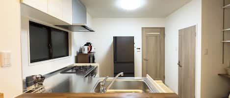 Een koelkast, een magnetron, een kookplaat, kookgerei, borden en bestek