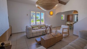 A spacious living room with a sofa, coffee table, and a dining area with chairs.