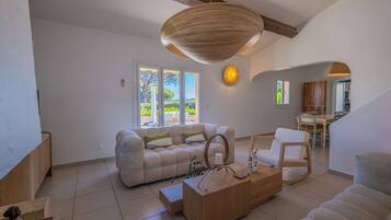 A spacious living room with a sofa, coffee table, and a dining area with chairs.