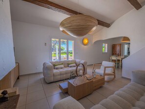 A spacious living room with a sofa, coffee table, and a dining area with chairs.