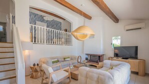 A living room with a sofa, a wooden rocking chair, a fireplace, a television, and a staircase.