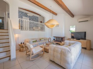 A living room with a sofa, a wooden rocking chair, a fireplace, a television, and a staircase.