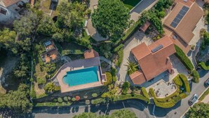 An aerial view of a residential area with a swimming pool, terraced houses, and surrounding greenery.