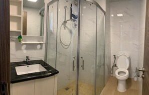 A bathroom with a glass-enclosed shower, a sink, and a toilet. - Morich suites BSD (Pagedangan)