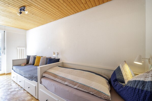Une chambre avec un plafond en pente, un lit avec de nombreux oreillers, une lampe de chevet et une fenêtre.