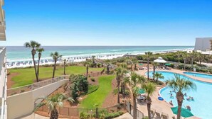 A resort with a pool, palm trees, and a beach view. - The Crescent 306 (Miramar beach)