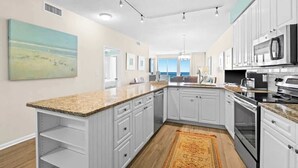 A modern kitchen with white cabinets, granite countertops, and stainless steel appliances. - The Crescent 306 (Miramar beach)