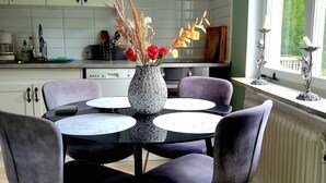 Una cocina moderna con armarios blancos, una mesa de comedor con sillas y un florero con flores.