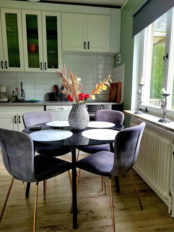 Une cuisine moderne avec des meubles blancs, une table à manger avec des chaises et un vase rempli de fleurs.