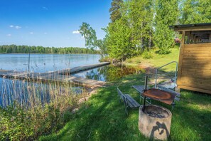 Un chalet au bord du lac, doté d’un quai s’avançant dans l’eau, entouré de verdure et d’arbres.