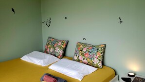 Una cama con almohadas estampadas, un edredón amarillo y toallas enrolladas.